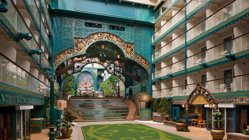 Stateroom balconies overlooking Disney Imagination Garden on the Disney Adventure cruise ship, featuring a landscaped courtyard and grand staircase