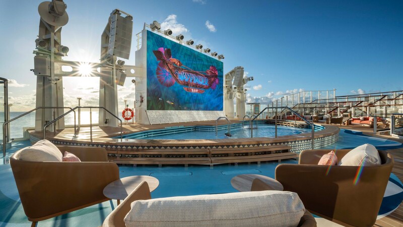 A large movie screen above a pool in Wayfinder Bay on the Disney Adventure cruise ship