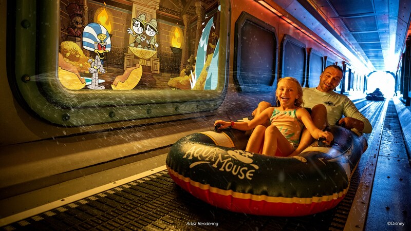 A father and daughter riding in an inflatable raft through a tunnel with Mickey Mouse cartoons displayed on the walls 