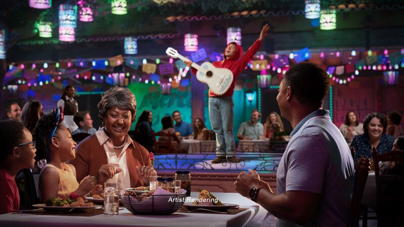 A family eating at a Plaza de Coco dining table while Miguel serenades the crowd from a stage