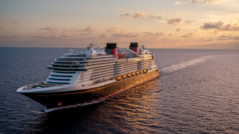 A Disney Cruise Line ship sailing on calm waters at sunset