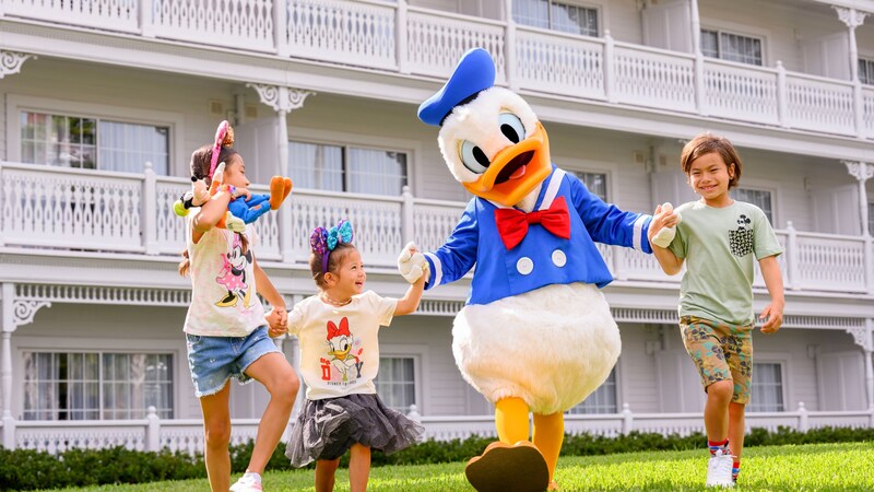 Three kids holding hands with Donald Duck near Disney's Grand Floridian Resort & Spa