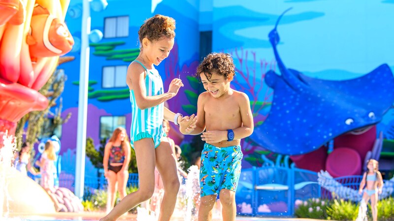 Two children holding hands as they splash in the Flippin’ Fins Pool at Disney's Art of Animation Resort
