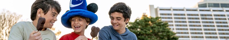 Three boys eating Mickey Mouse ice cream bars in front of Disney’s Contemporary Resort