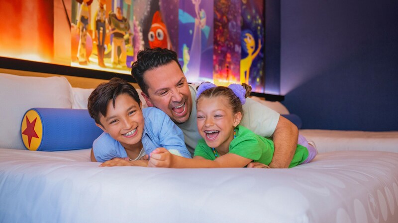 A father and his 2 kids play around in a Disneyland Resort hotel room
