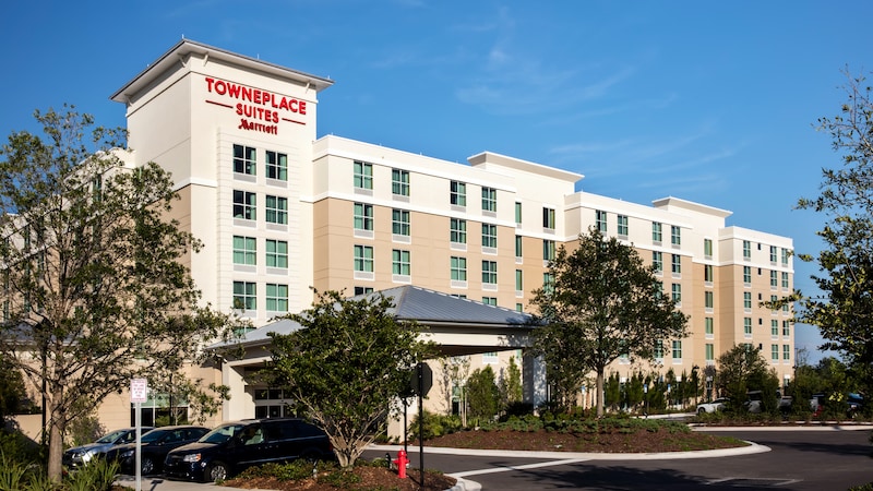 A driveway leads to a low rise hotel with a sign identifying it as the TownePlace Suites Marriott