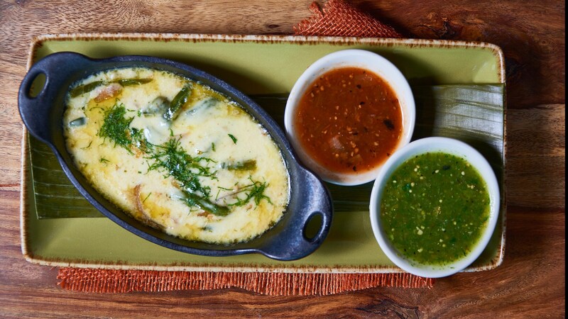 A melted cheese dish with roasted poblanos and caramelized onions is served with 2 types of salsa
