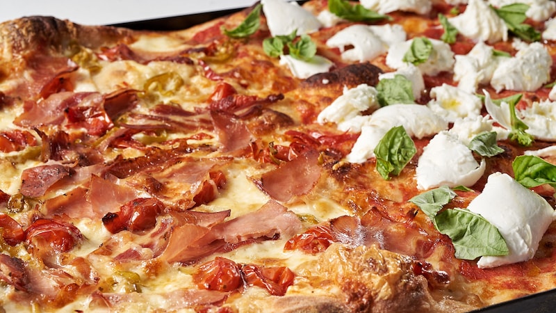Pizza topped with mozzarella, tomatoes and prosciutto