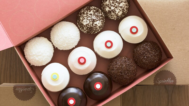 A dozen assorted cupcakes neatly displayed in a signature Sprinkles box