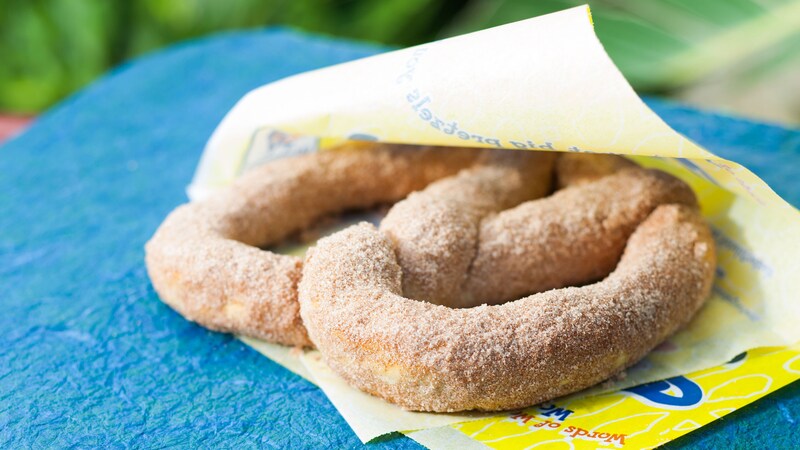 A large, doughy pretzel in a Wetzel's wrapper is covered in cinnamon and sugar