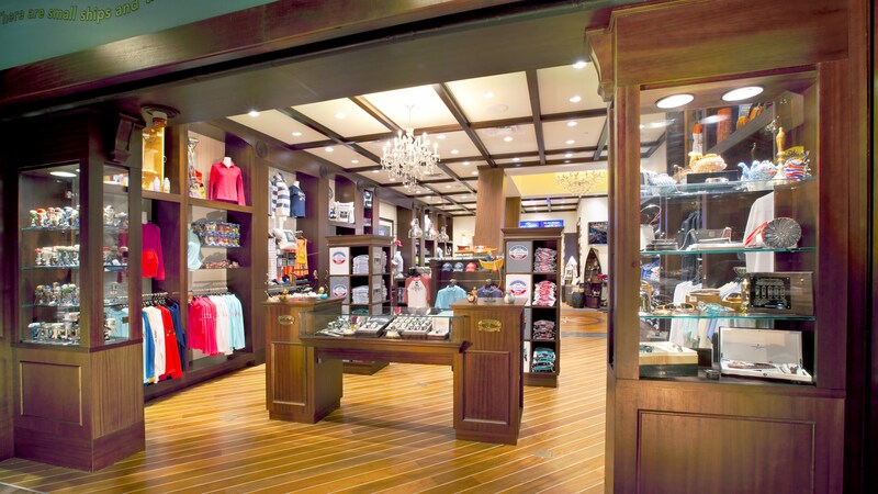 A boutique with wooden floors and cabinets displays clothing, jewelry, gifts and accessories