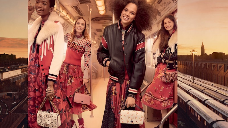 Four women carry Coach handbags and stand inside a train car