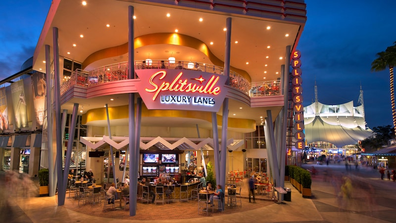 Exterior view of the 2 story Splitsville Luxury Lanes at Disney Springs West Side shows Guests eating outdoors at night