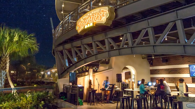 The Stargazers Bar open air patio at Planet Hollywood Observatory at night with Guests seated at tables and a musician setting up