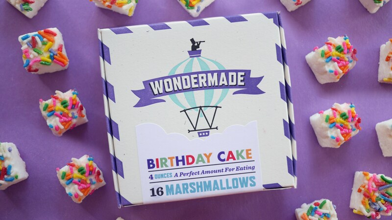 A box of 16 Birthday Cake flavored Wondermade marshmallows, surrounded by marshmallow squares topped with colorful sprinkles.