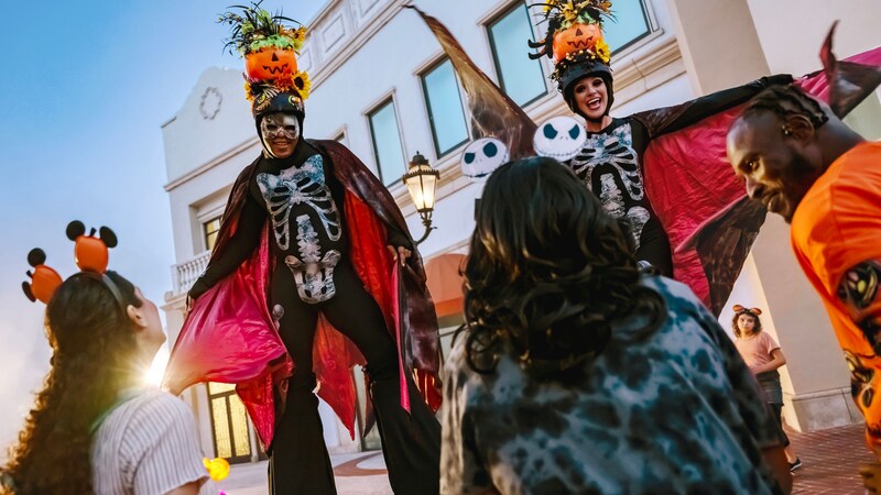 Halloween themed stilt walkers in skeleton costumes and pumpkin headpieces at Disney Springs