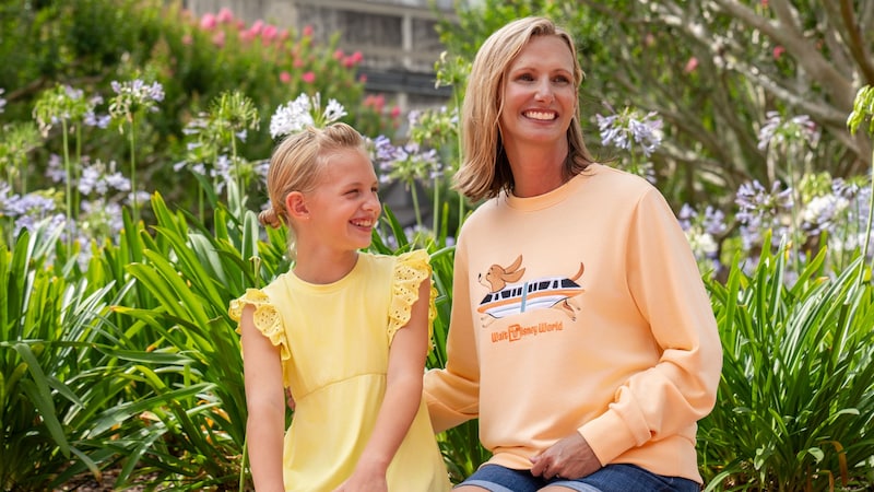 A young girl sitting beside her mother who is wearing a sweatshirt from the Disney Cats and Dogs Halloween Collection
