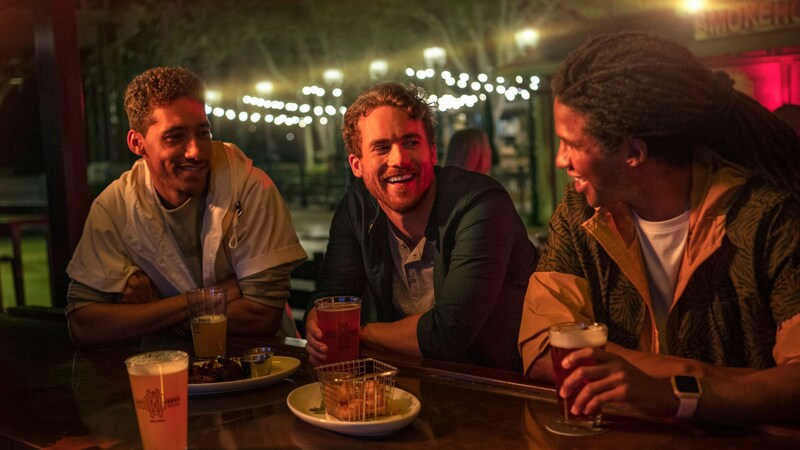 Three friends sitting at a table together enjoying food and drinks at City Works in Disney Springs