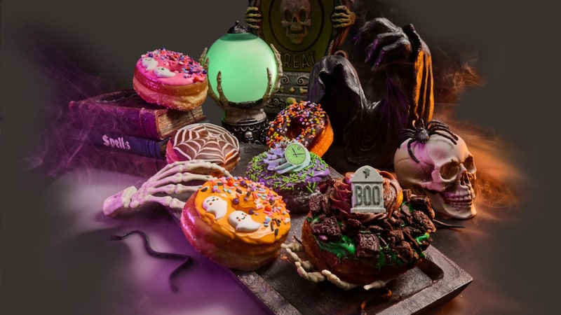 An assortment of Halloween themed donuts surrounded by props and skulls from Everglazed Donuts & Cold Brew