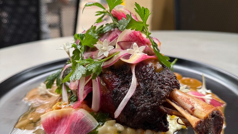 A shank of lamb served with sweet corn risotto