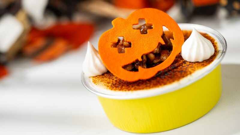 A Pumpkin Spiced Creme Brulee with whipped cream and a pumpkin shaped topper
