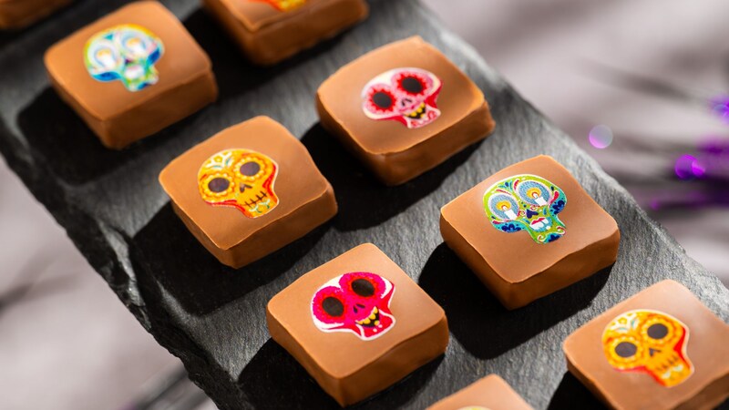 Day of the Dead sugar skull decorated chocolates arranged on a slate board from The Ganachery