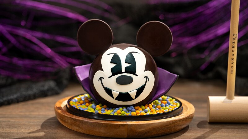 A vampire Mickey Mouse chocolate pinata plated next to a wooden mallet
