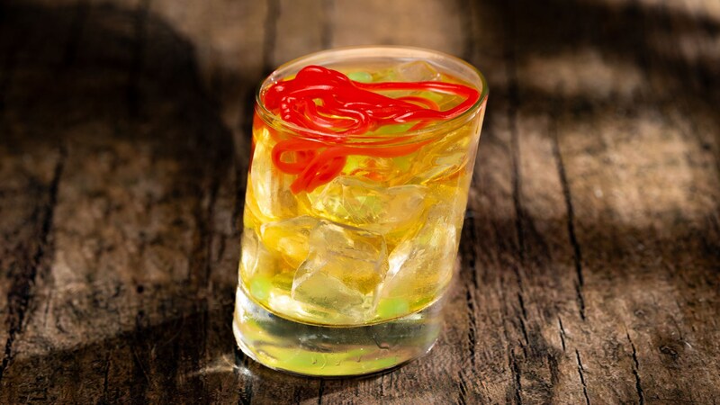 A cocktail in a slanted glass, topped with gummy worms