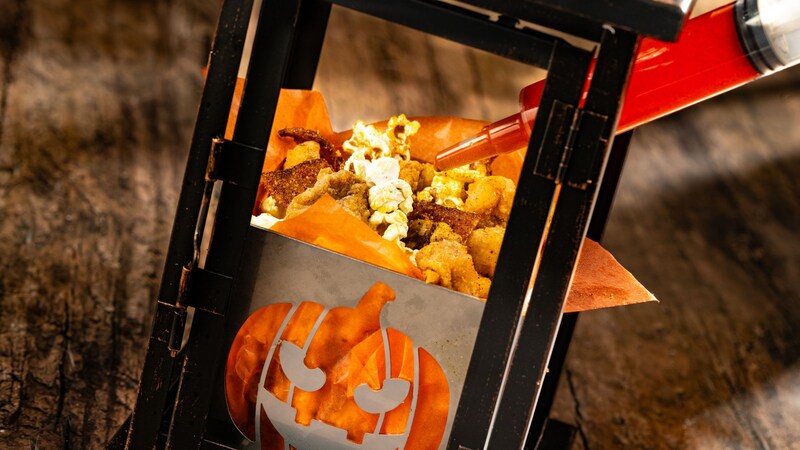 A lantern holding popcorn chicken next to a syringe of sauce  