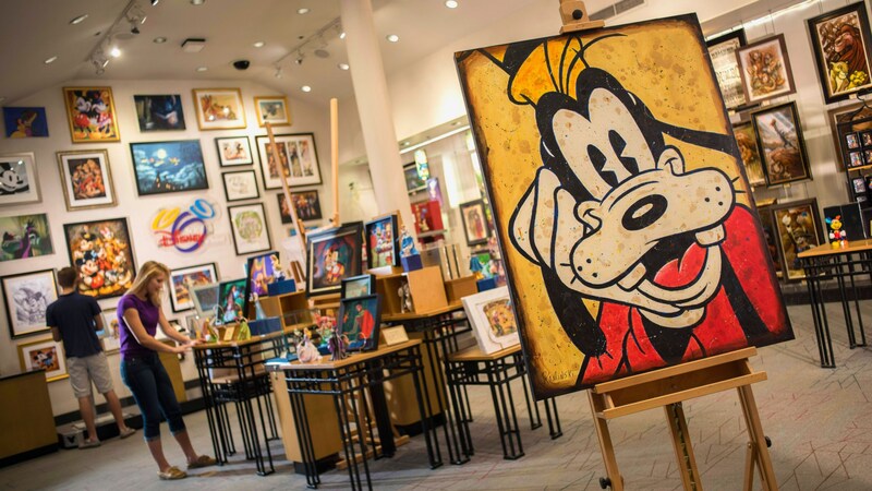 Una pintura grande de Goofy en una tienda de arte con un letrero en la pared que dice “Art of Disney”