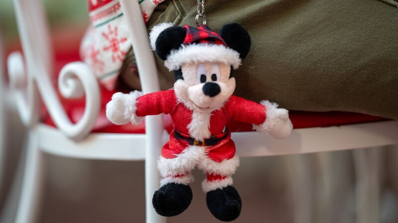Un Visitante con un llavero de peluche de Mickey Mouse vestido de Santa