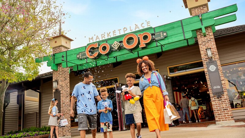 A family walking near the Marketplace Co Op at Disney Springs while holding Disney merchandise