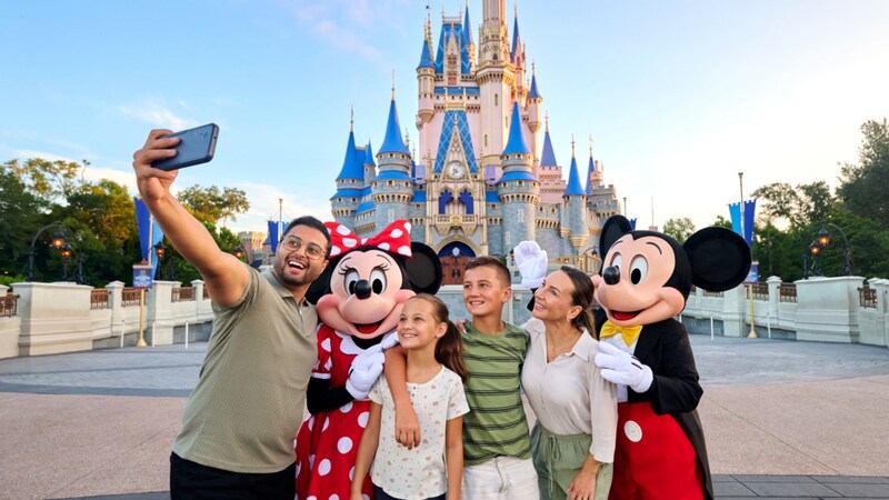 Una familia de 4 posando para una foto con Mickey Mouse y Minnie Mouse
