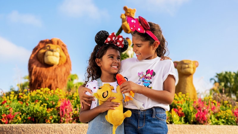 Two young Guests with Minnie Mouse ear headbands hugging in front of The Lion King topiaries at Epcot Flower & Garden Festival