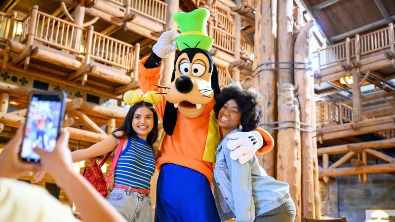 Goofy y 2 huéspedes posando para una foto en Disney’s Wilderness Lodge