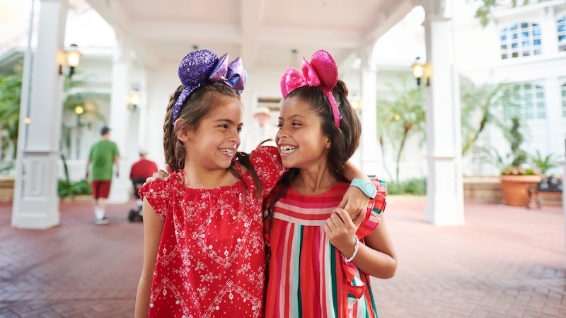 2 meninas usando tiaras com orelhas da Minnie Mouse posando do lado de fora do Disney’s Grand Floridian Resort & Spa