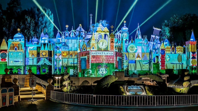 Vintage Disneyland imagery projected onto the façade of the it’s a small world attraction at night
