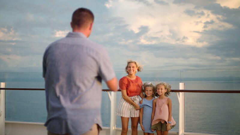 A father snapping a picture of his wife and 2 young daughters