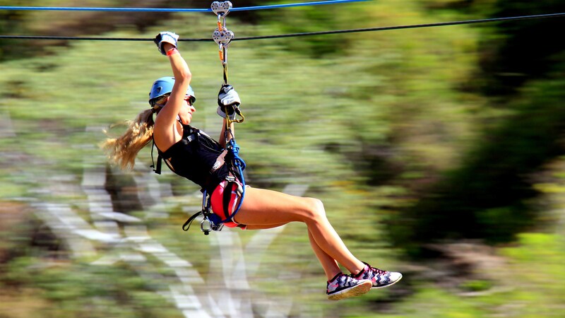 A woman zip lining through a forest