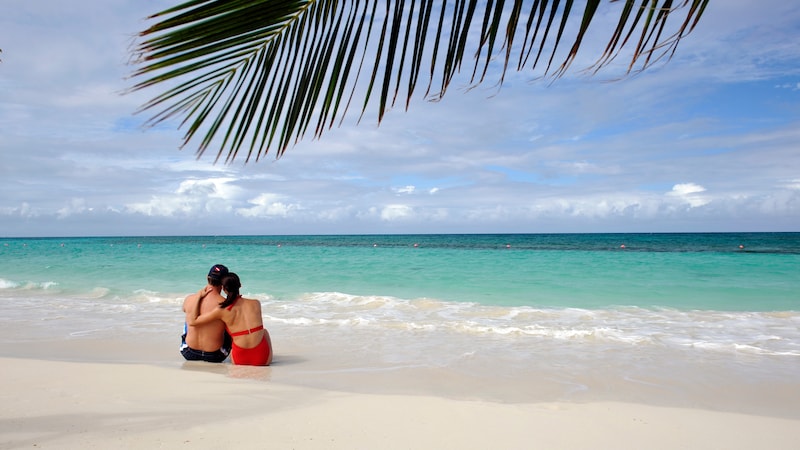 A couple sits along the shoreline of an adult only beach on Disney Castaway Cay in The Bahamas