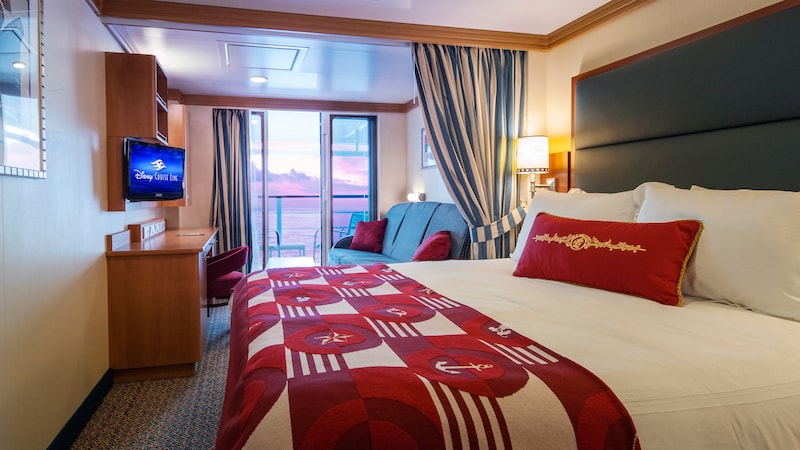 A stateroom featuring a bed, privacy curtain, sofa, desk, TV and verandah 