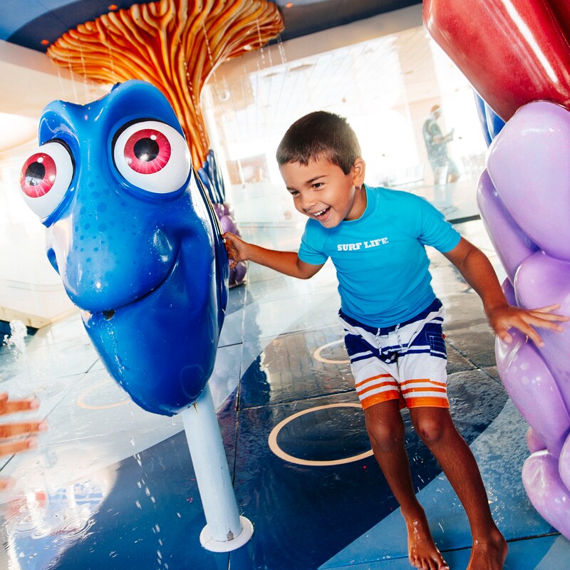 A small boy laughs while getting sprayed with water at Nemo's Reef 