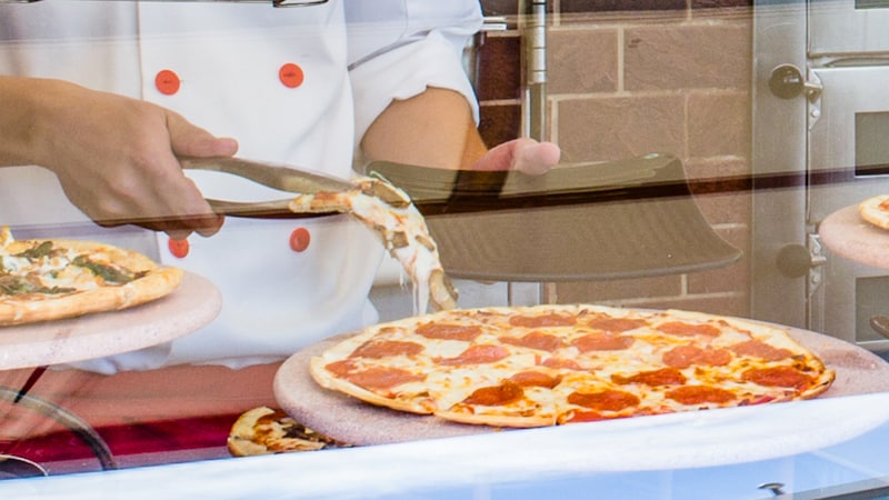 A server dishing up a slice of pepperoni pizza