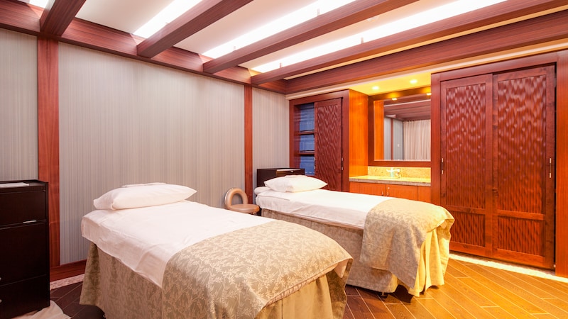 Treatment room featuring 2 treatment beds, built in wooden closets, wood floors and a mirror over sink
