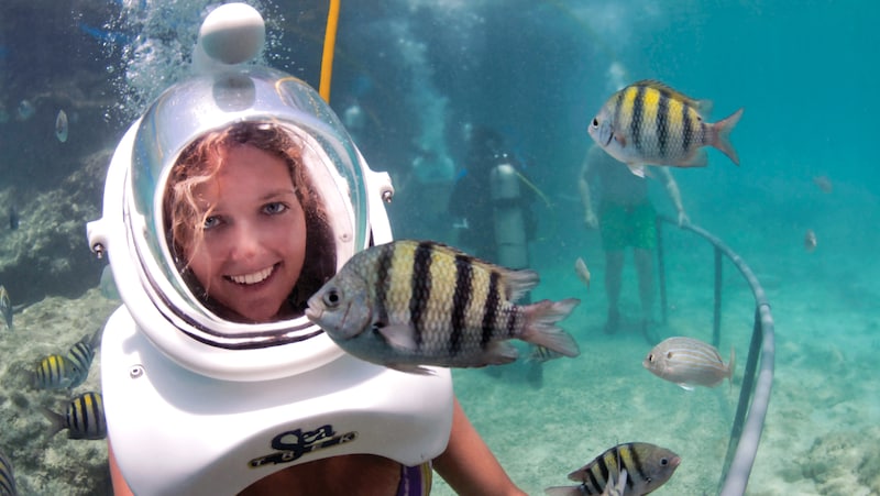 A women smiles as a striped fish swims past her during a Sea Trek Helmet dive