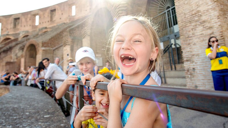 A group of children smiling outside a historical building