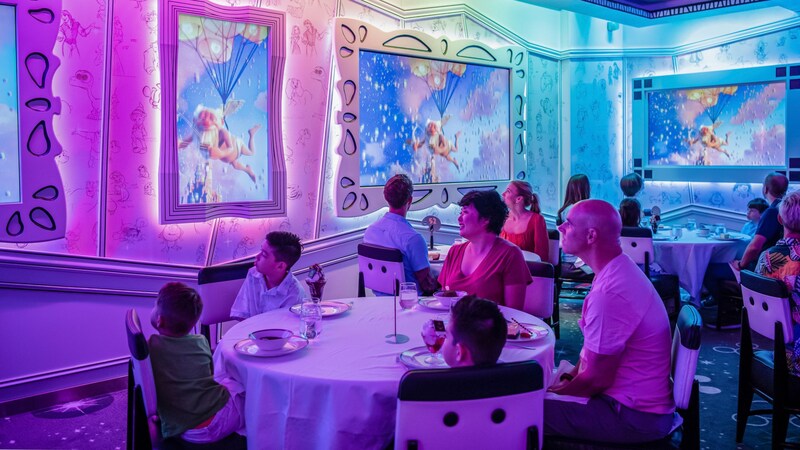 A young family of 5 enjoying a meal while admiring animation on the walls of Animator’s Palate