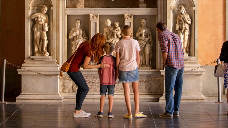 A family of 4 admiring marble statues in a museum setting in Barcelona, Spain