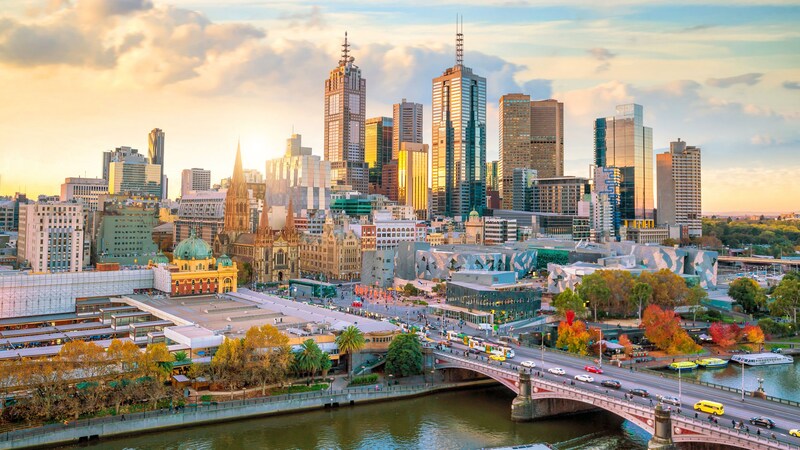 The Melbourne skyline reveals tall glass and steel buildings next to a river and bridge