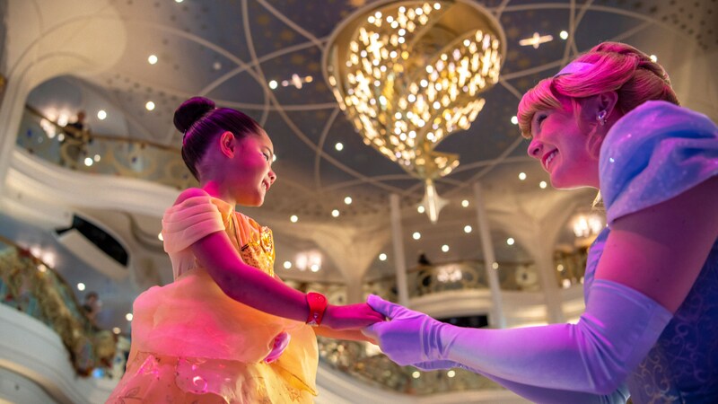 The Disney Character Cinderella holding hands with a child wearing a Disney Princess costume
